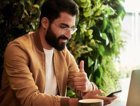 Man working on laptop giving thumbs up